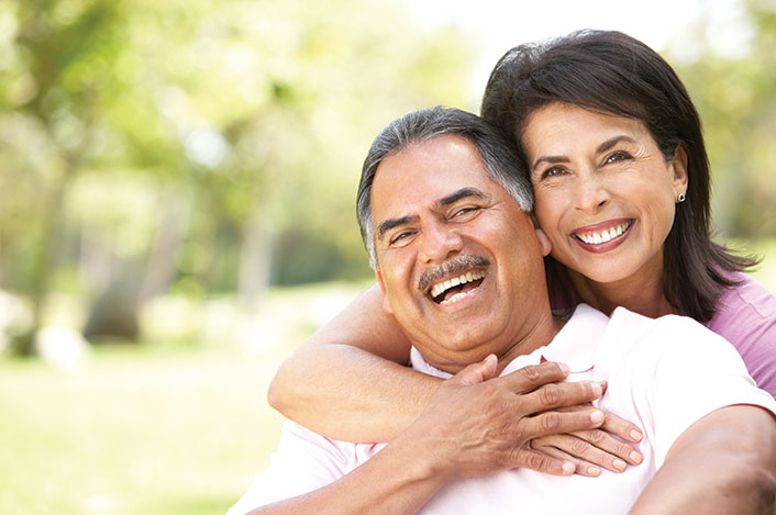 A woman hugging her husband from behind. Links to Gifts of Appreciated Securities