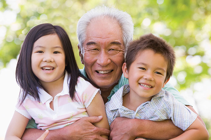 A man hugs his two grandchildren closely. Links to Gifts of Life Insurance